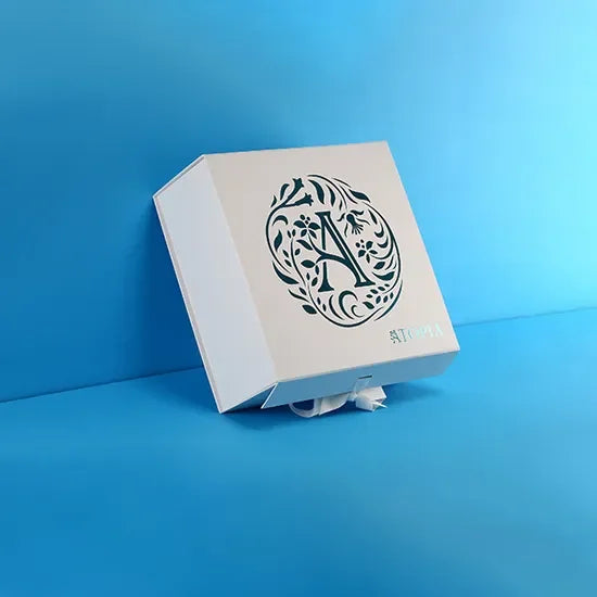 Collapsible white gift box with magnetic closure and floral monogram design on lid