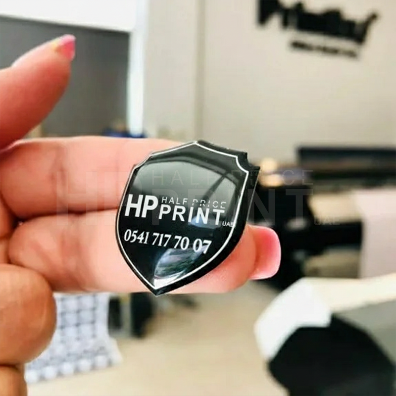 Person holding a black and white shield-shaped card with Half Price Print branding.