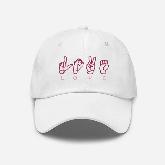 White embroidered cap with pink love sign language design on front, Sharjah UAE.