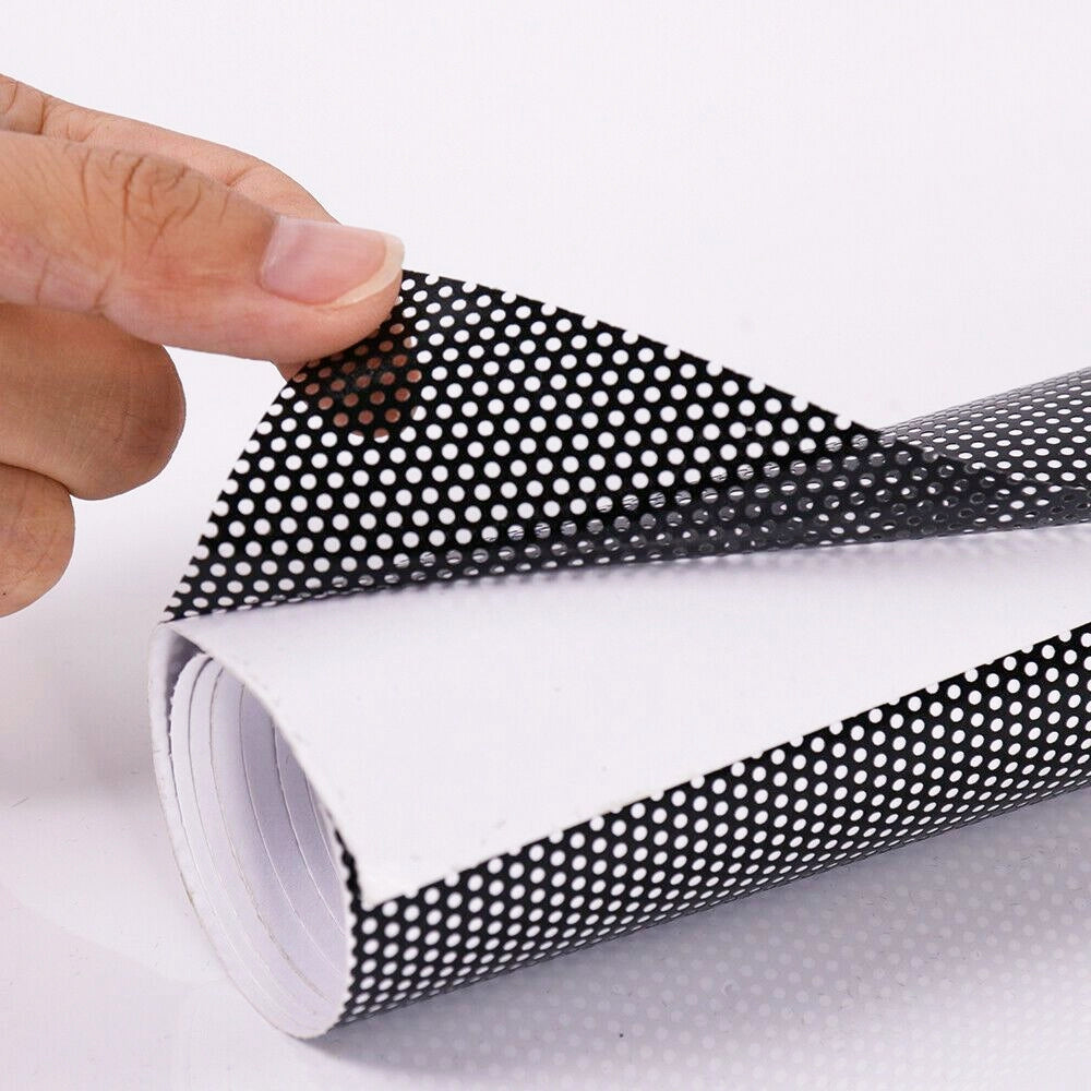 Roll of black and white polka dot patterned paper held by a hand on a light gray background