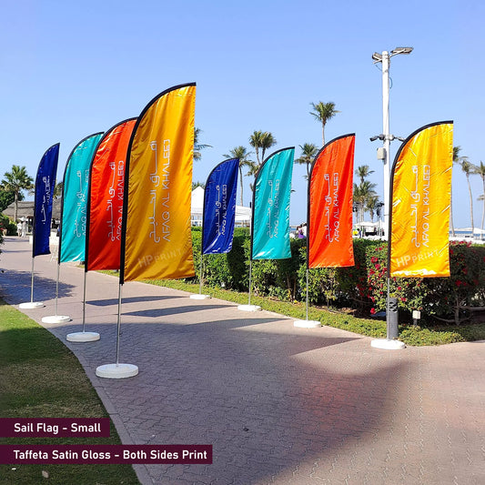 Colorful sail flags on poles with a clear blue sky and palm trees in the background.