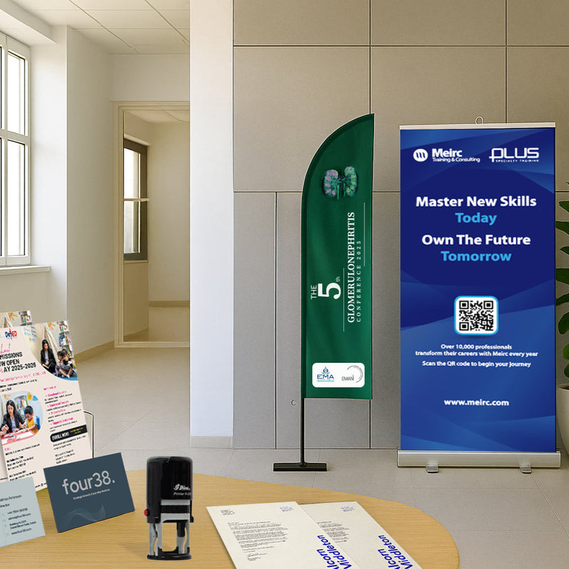 Promotional materials including a banner, leaflets, and a standee on a table in an office setting.