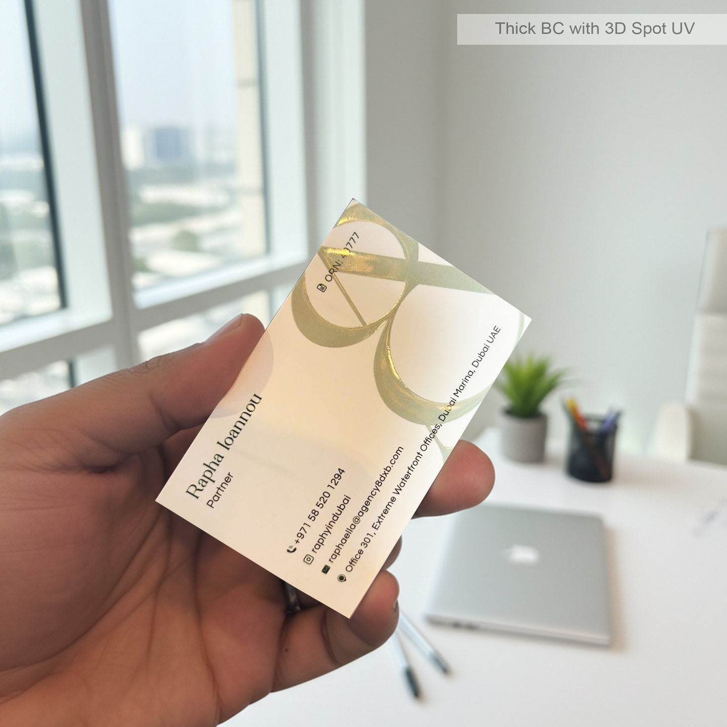 Hand holding a thick business card with a blurred office background