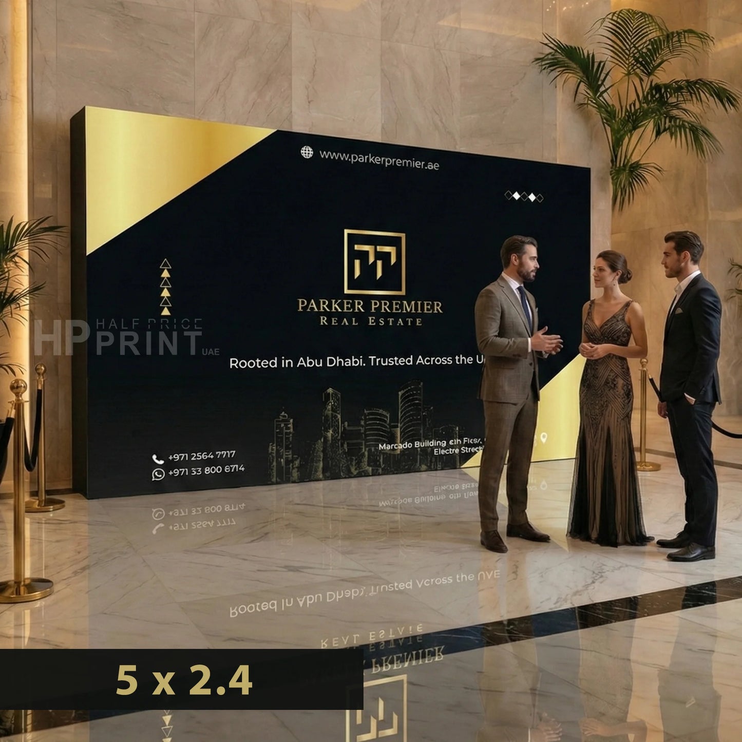 Two men and a woman standing in front of a large wooden backdrop displaying Parker Premier Real Estate in a luxurious lobby.