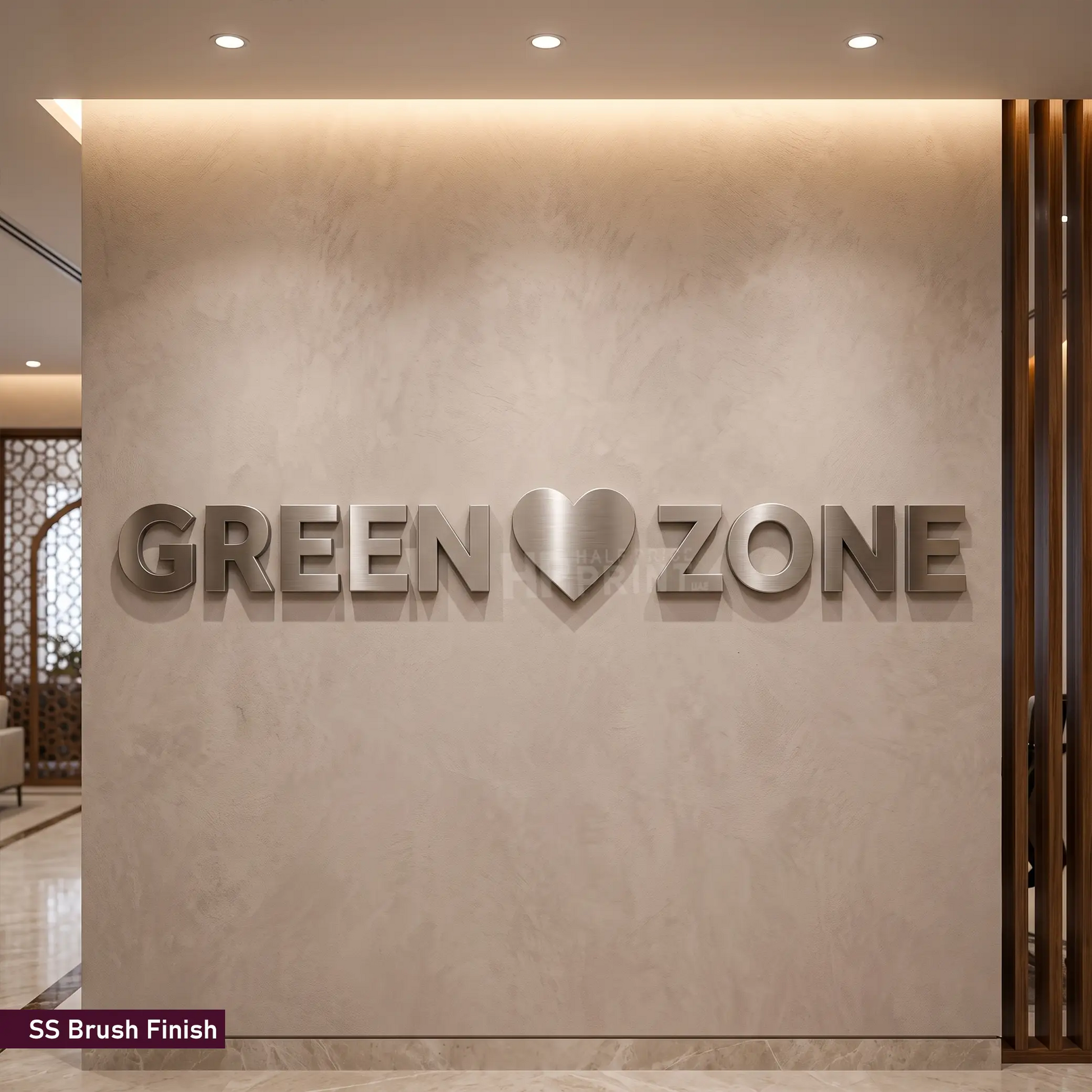 3D metal wall art featuring the text 'GREEN' and 'ZONE' with a heart symbol in the center, mounted on a textured beige wall. The letters have a brushed silver finish, and a small label in the bottom-left corner reads 'SS Brush Finish'.