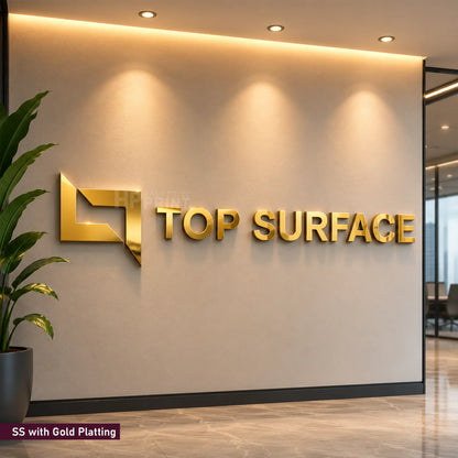 Gold metallic 3D logo wall sign reading 'TOP SURFACE' mounted on a beige office wall, with warm recessed lighting above and a plant at the left edge.