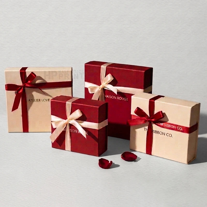 Five gift boxes in two colors: deep red and beige. Three red boxes are wrapped in beige satin ribbon with red bows, and two beige boxes are wrapped in red satin ribbon with beige bows.
