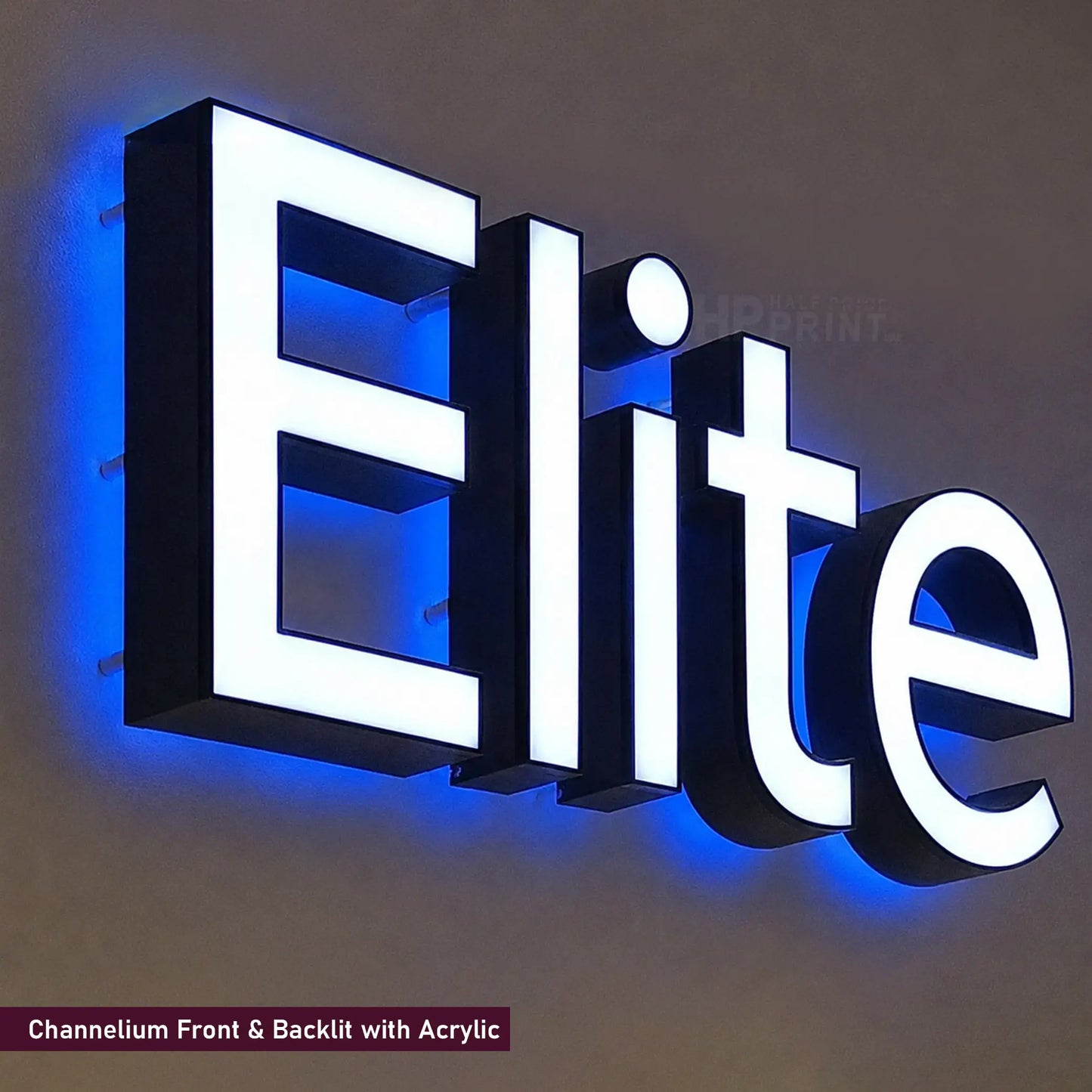 A 3D acrylic LED sign spelling 'Elite' with white illuminated letters and a blue channellit backlit effect, mounted on a dark wall.