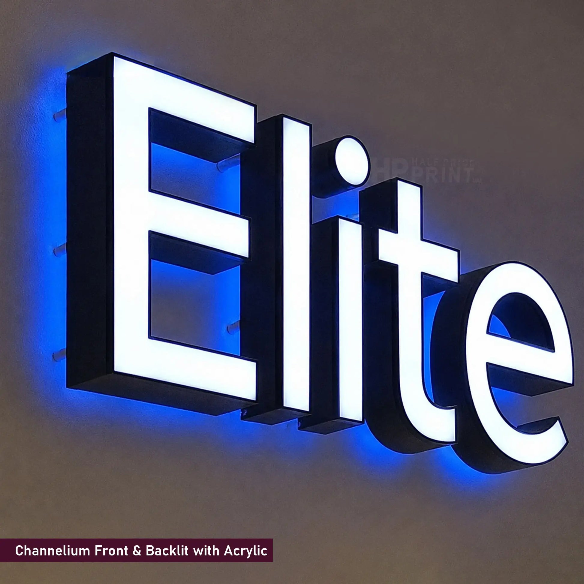 A 3D acrylic LED sign spelling 'Elite' with white illuminated letters and a blue channellit backlit effect, mounted on a dark wall.