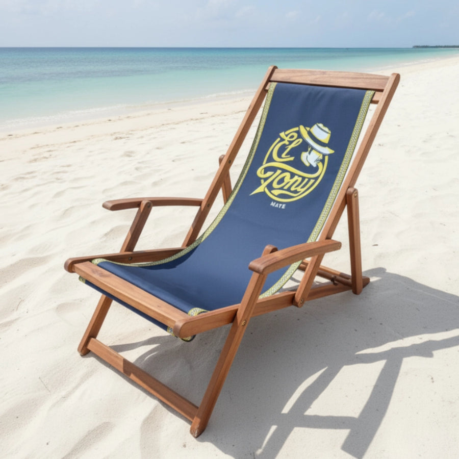 Beach chair with blue fabric and wooden frame on a sandy beach