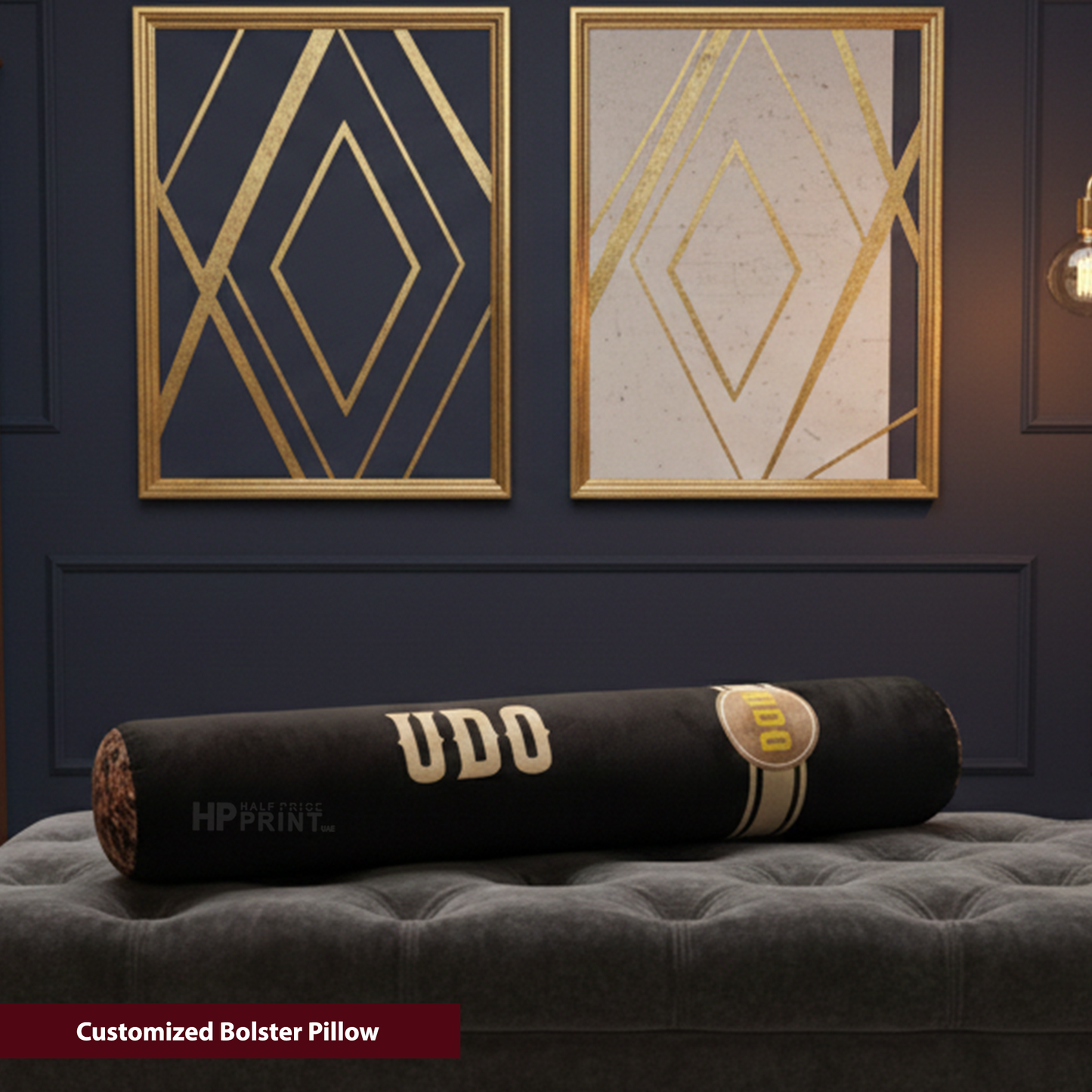 Customized bolster pillow with 'UDO' branding on a gray surface, framed geometric art in the background.