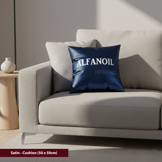 Navy blue satin cushion with 'ALFANOIL' branding on a beige sofa.