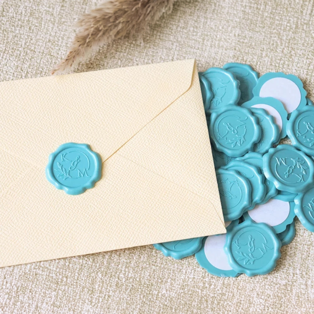 A collection of blue wax seal adhesive stickers next to an envelope on a beige background.