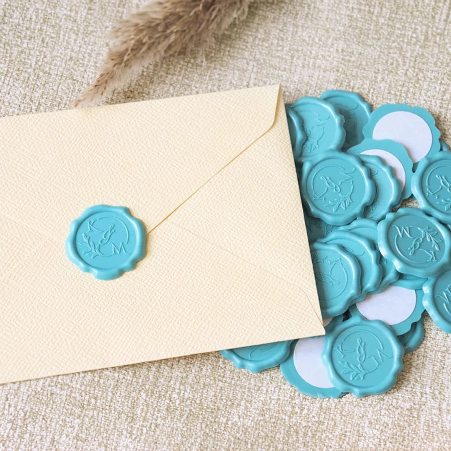 A collection of blue wax seal adhesive stickers next to an envelope on a beige background.