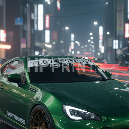 Green sports car on a city street at night with windshield stickers