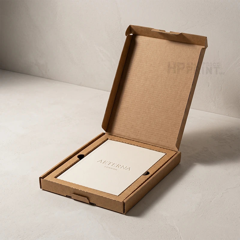 An open brown cardboard presentation box on a light gray surface, containing a white card printed with the brand name AETERNA.