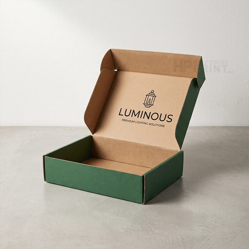 An open cardboard tab lock box with a green outer flange and brown inner liner. The inside lid is printed with the brand name 'LUMINOUS' and a small lantern icon.