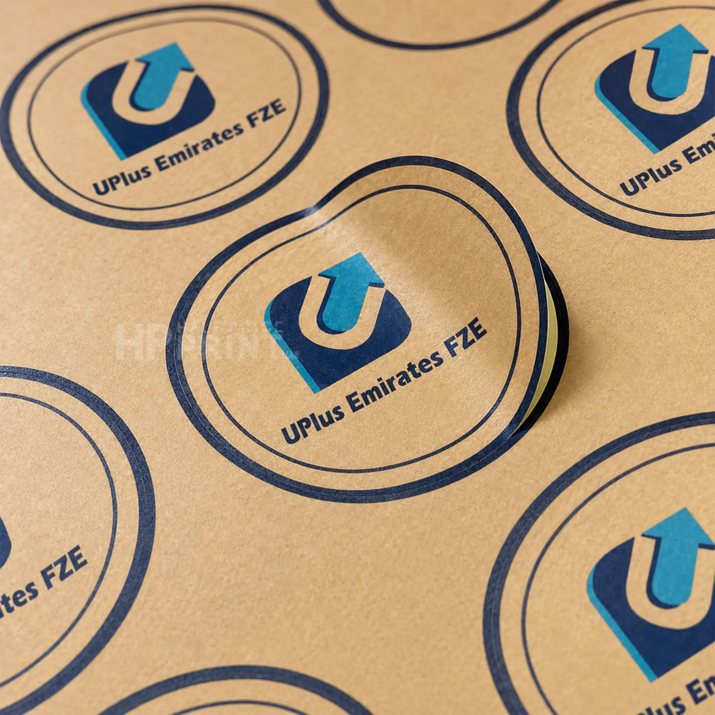A close-up of a brown kraft paper surface printed with repeated oval UPlus Emirates FZE logos in blue and white, with one central logo slightly raised.