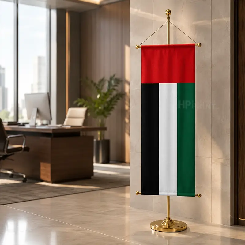 A vertical conference flag with the United Arab Emirates flag design, mounted on a gold-colored stand in a modern office lobby.