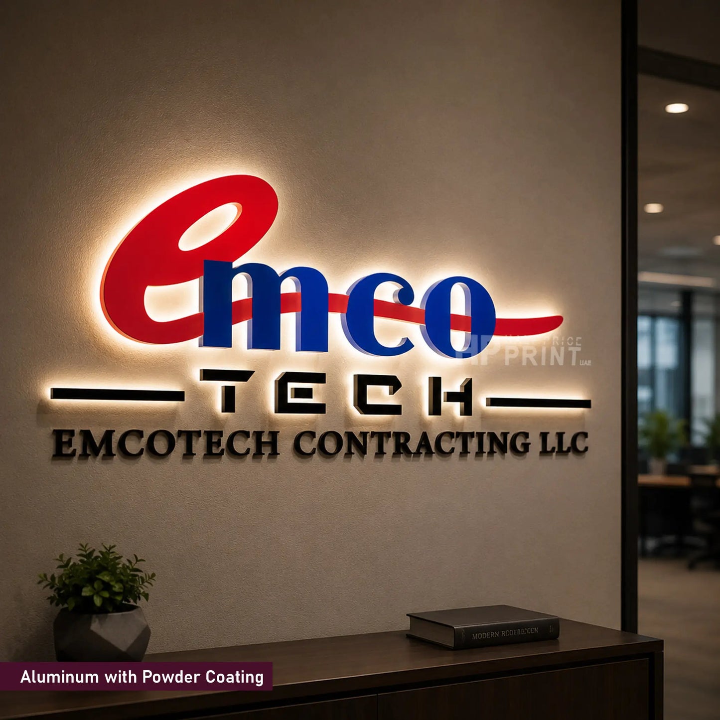 A custom LED backlit aluminum sign displaying 'emco TECH EMCOTECH CONTRACTING LLC' in red, blue, and black lettering, mounted on a beige wall in an office environment.