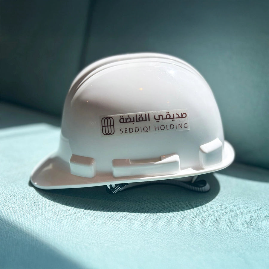 A white safety helmet with the Seddiq Holding logo printed on the front.