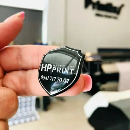 Person holding a black and white shield-shaped card with Half Price Print branding.