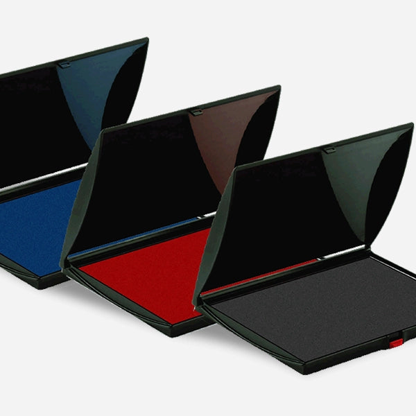 Three stamp pads in black, blue, and red colors, with their lids open, displaying the ink inside.