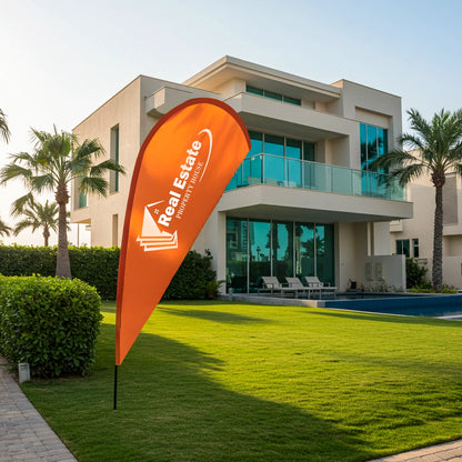 Orange real estate flag in front of a modern building with palm trees