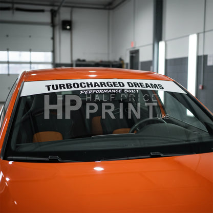 Orange car with a custom windshield banner in a garage