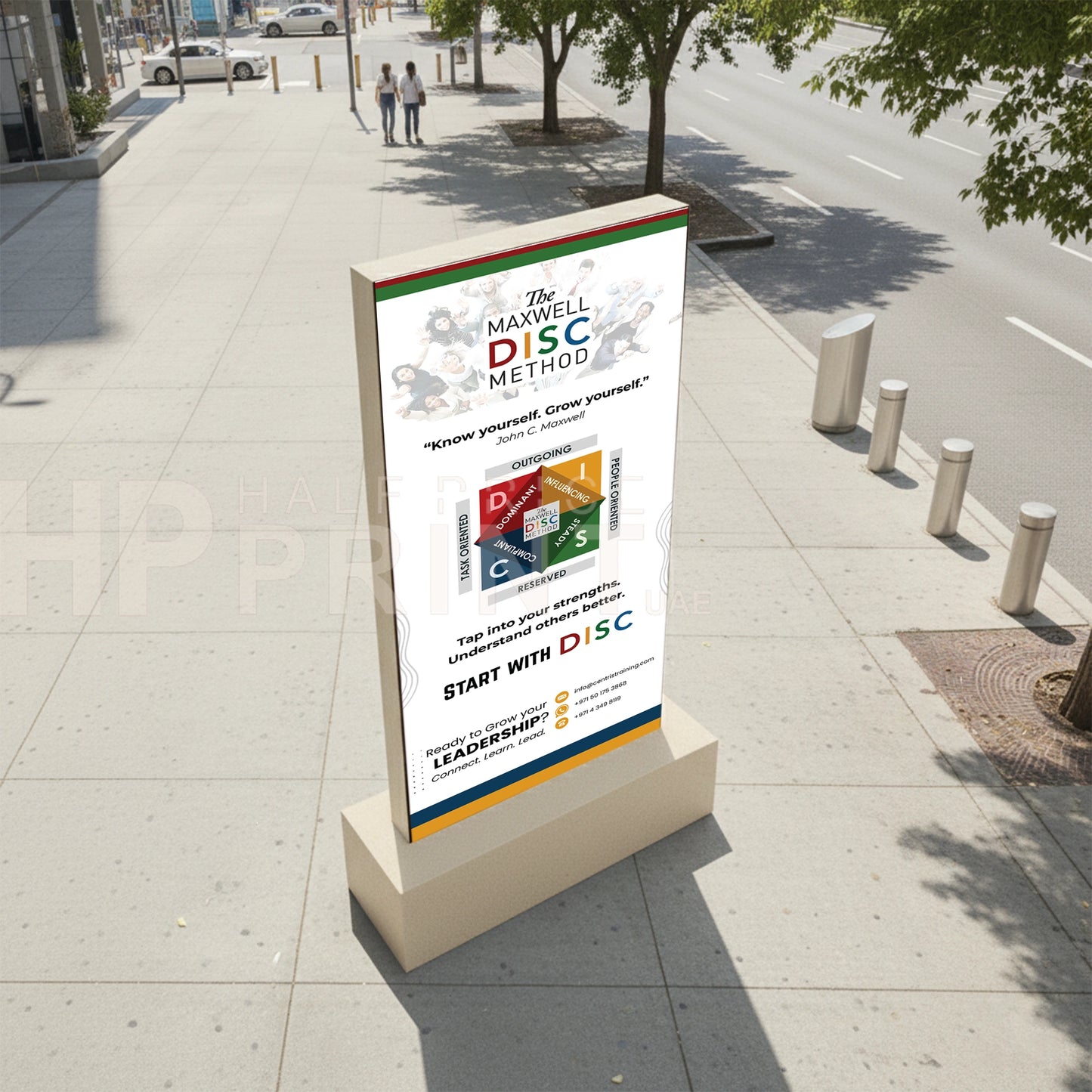 Digital totem display stand on a sidewalk with an advertisement for 'The Maxwell DISC Method' on a city street.