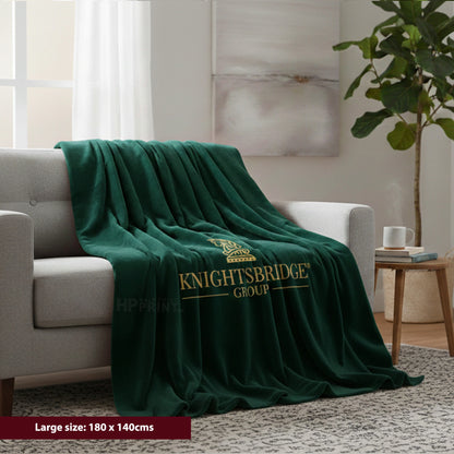 Green blanket with 'Knightsbridge Group' logo draped over a sofa in a living room.