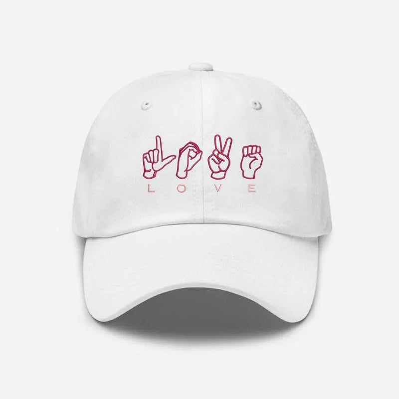 White embroidered cap with pink love sign language design on front, Sharjah UAE.