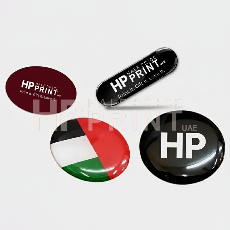 Half Price Print branded items including a round badge with UAE flag design and two rectangular epoxy stickers.