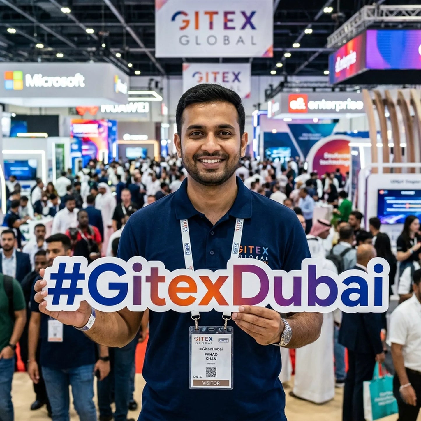 Man holding a '#GitexDubai' sign at a busy convention center with various booths and people in the background.
