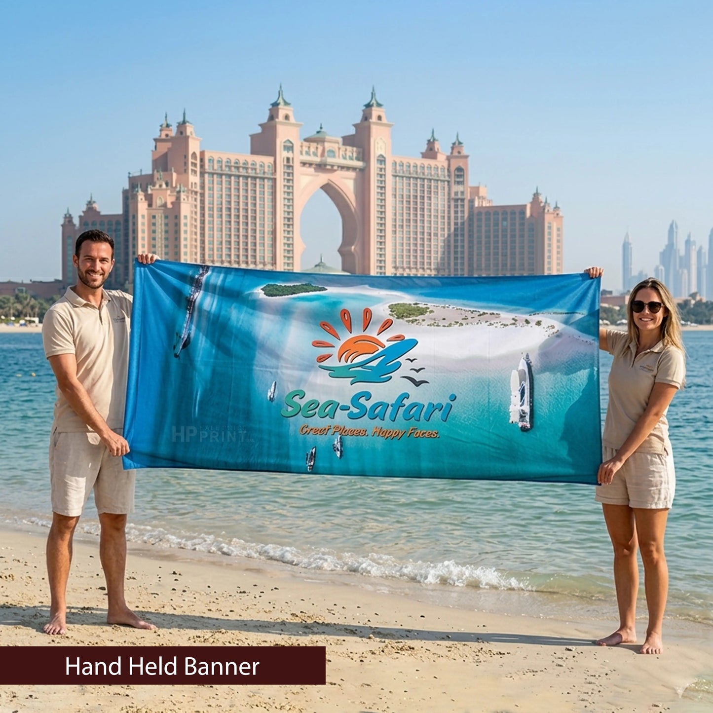 Two people holding a 'Sea-Safari' banner on a beach with a cityscape in the background