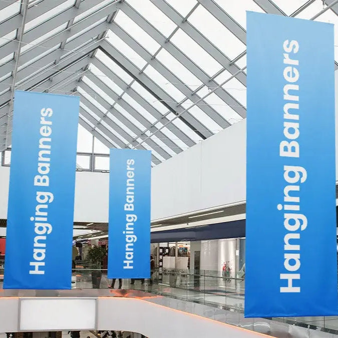 Three blue hanging banners with white text 'Hanging Banners' displayed in atrium setting.