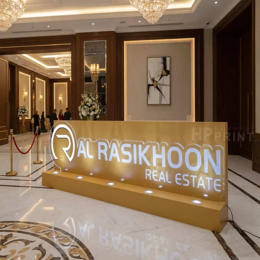 Al Rasikhoon Real Estate sign in a luxurious lobby with chandeliers and marble floors.