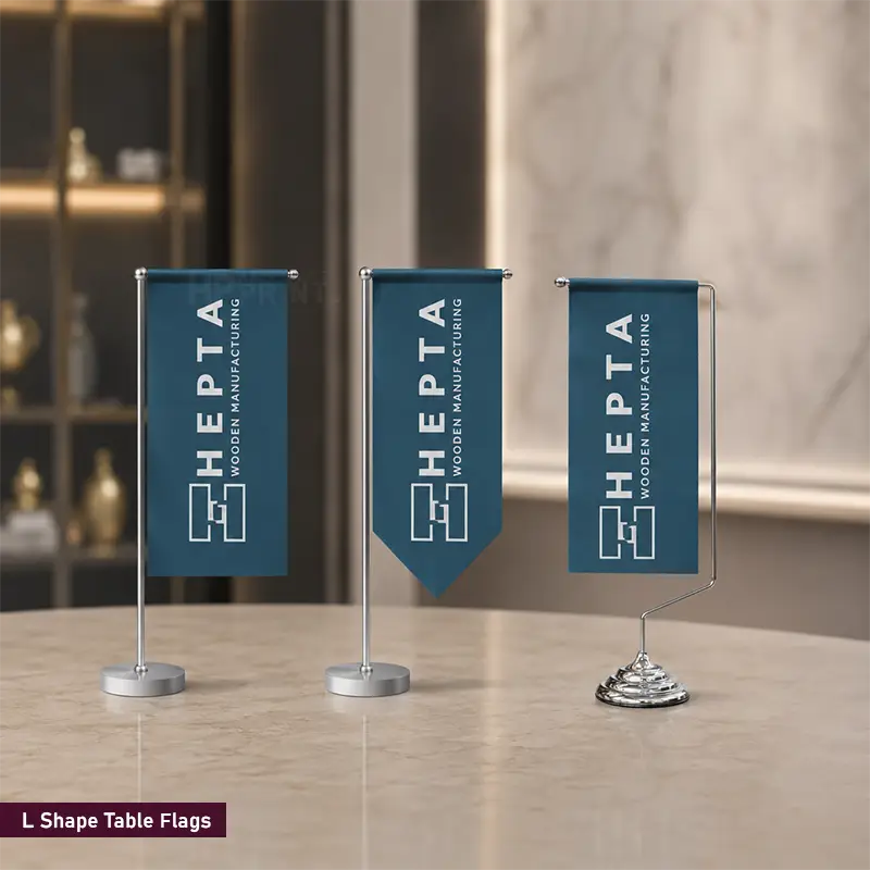 Three blue L-shape table flags with silver metal stands displayed on a light marble tabletop in an indoor setting. The flags feature the text 'HEPTA WOODEN MANUFACTURING' in white.
