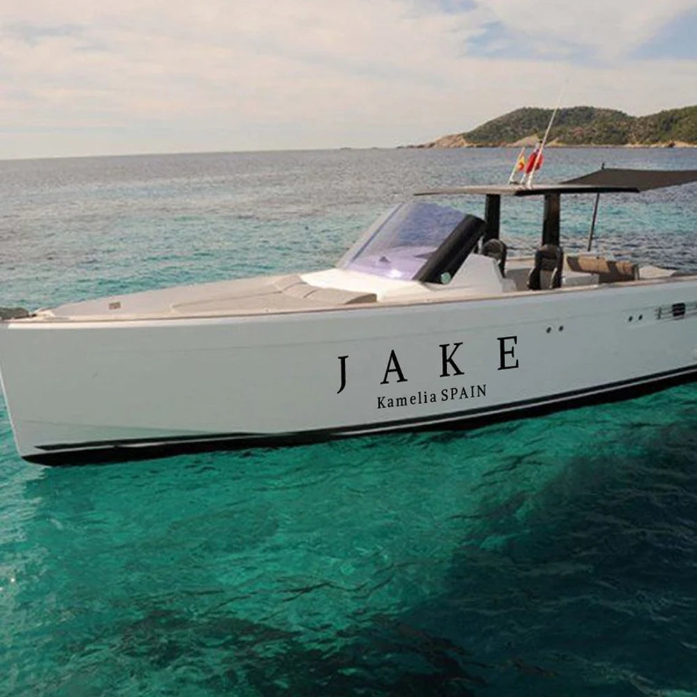 A boat on water with the name 'JAKE' printed sticker on its side, with a beautiful landscape in the background.