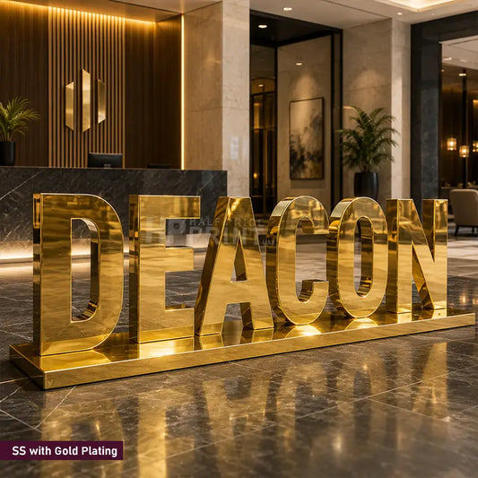 Large gold-plated freestanding letters spelling DEACON placed in a modern lobby or reception area, with polished marble flooring and warm interior lighting in the background.