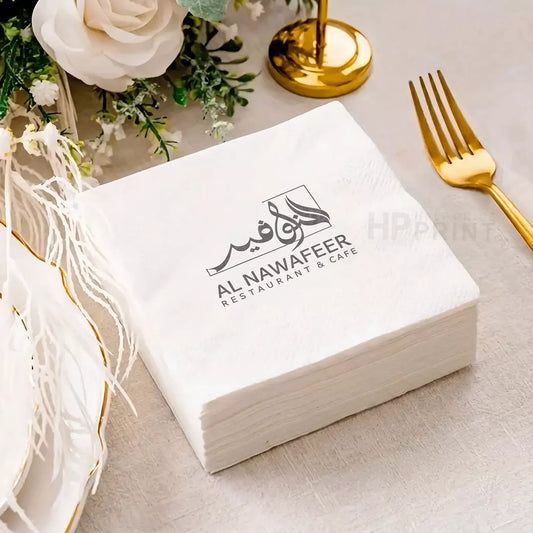 Box of Al Nawafeer Restaurant & Cafe napkins on a table with decorative elements.