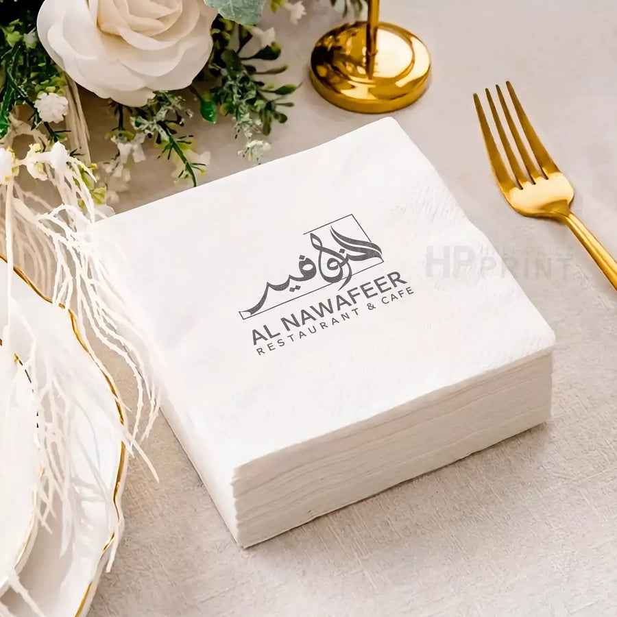 Box of Al Nawafeer Restaurant & Cafe napkins on a table with decorative elements.
