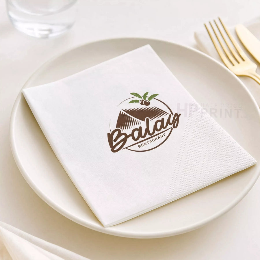 Napkin with Balau Restaurant logo on a white plate with cutlery