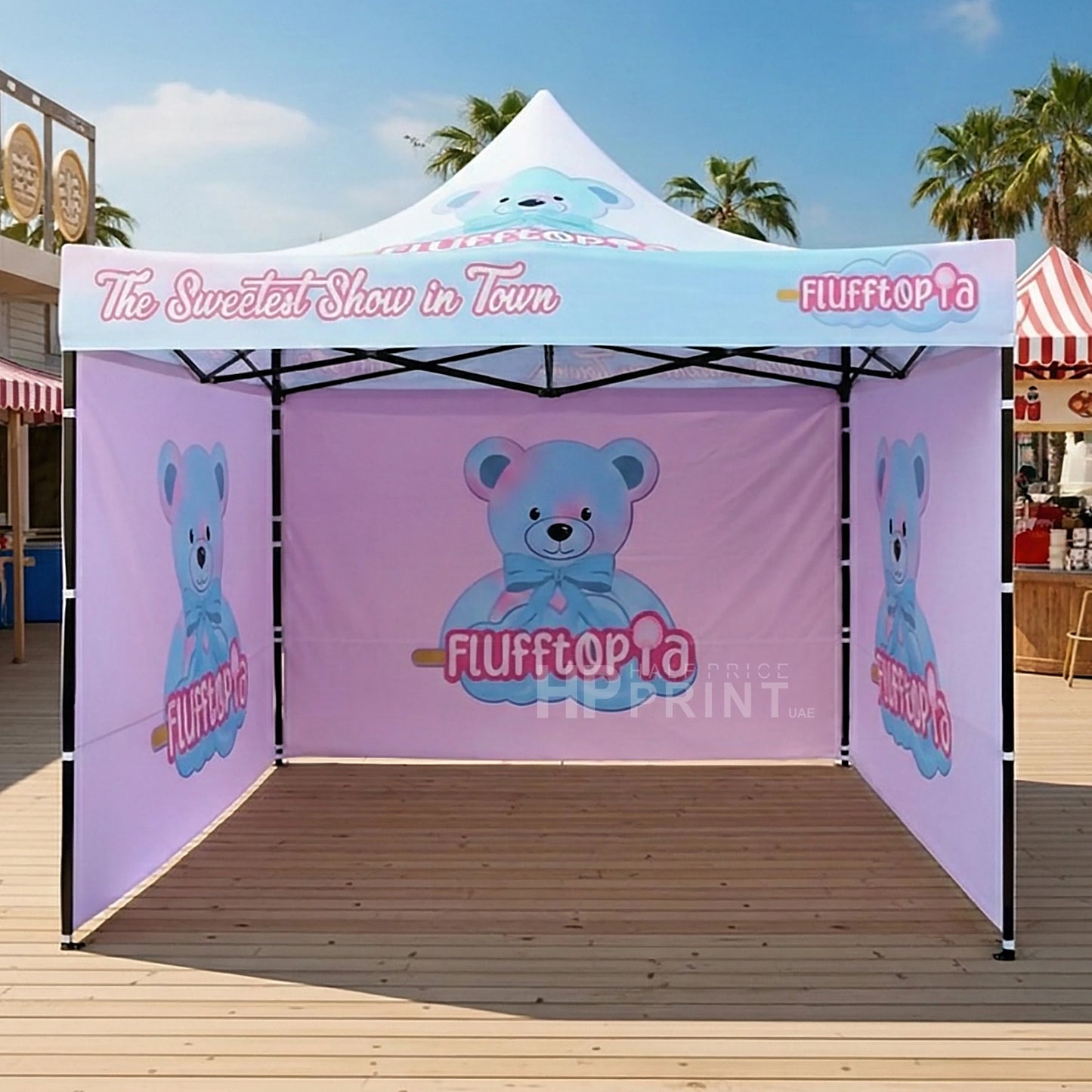 Outdoor canopy tent with 'Flufftopia' branding and teddy bear graphics on a wooden deck.