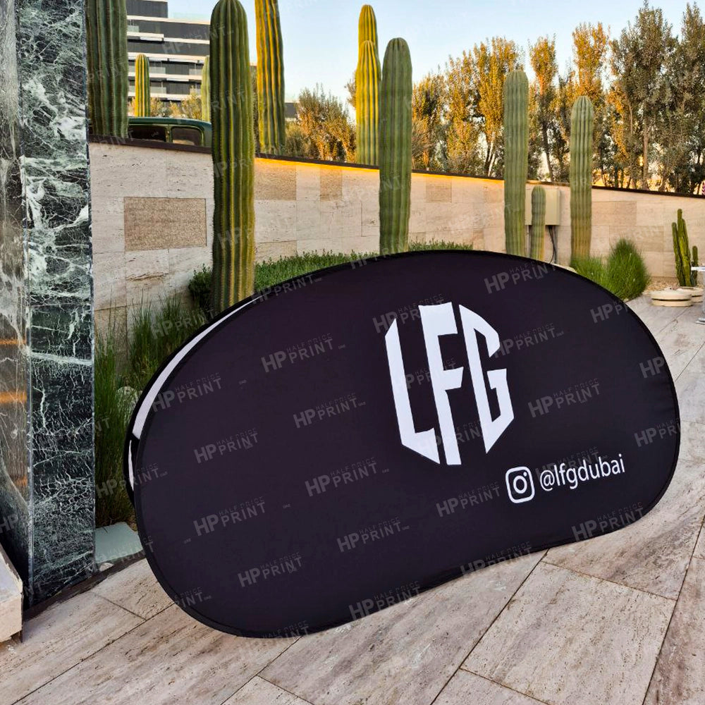 Black oval sign with 'LFG' and social media handle on a stone surface with cacti in the background