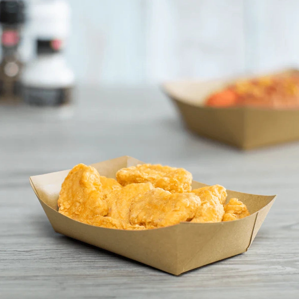 A paper food tray filled with fried chicken pieces on a wooden surface with a blurred background.