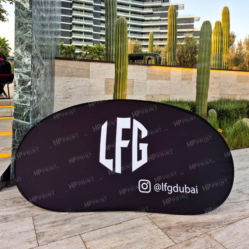 Black banner with 'LFG' logo and '@lfdgduabi' text on a sidewalk with cacti and buildings in the background.