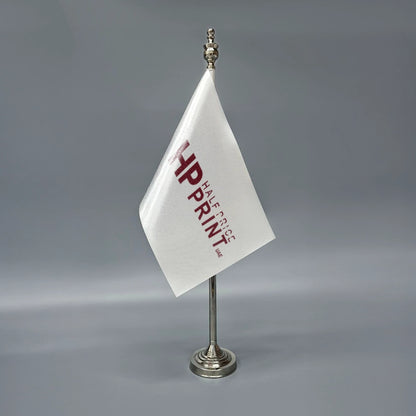 A white table flag with red text, mounted on a metal stand.