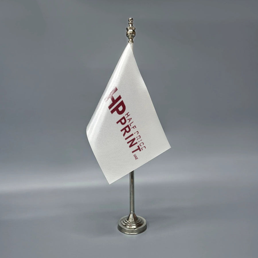 A white table flag with red text, mounted on a metal stand.