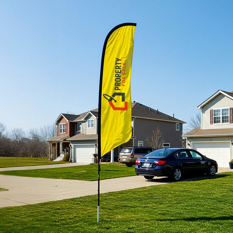 Yellow 'For Sale' flag in front of a house with cars parked in the driveway.